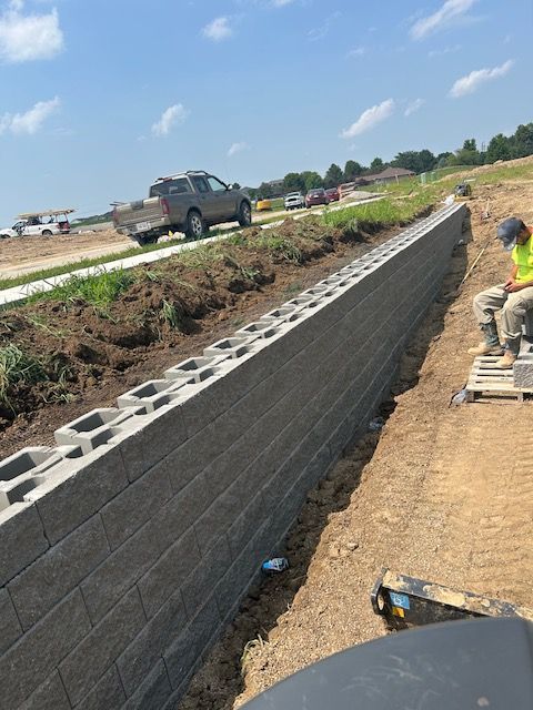 A man is sitting on a pallet next to a brick wall.