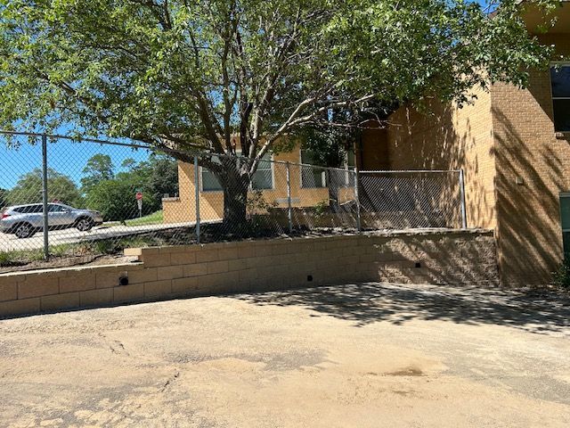 A car is parked in front of a building next to a tree.