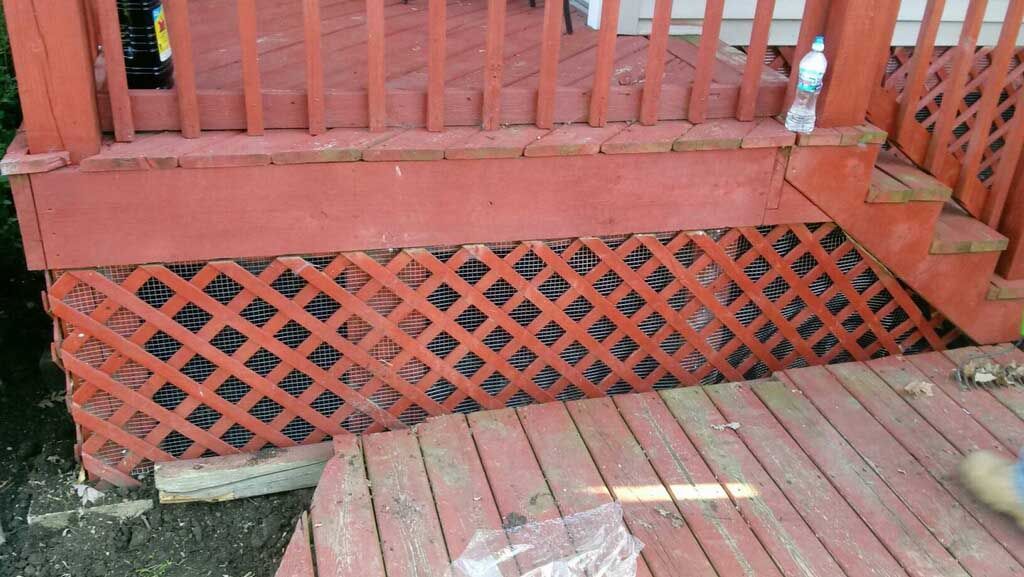 Red wooden porch with lattice skirting and steps, viewed from a deck