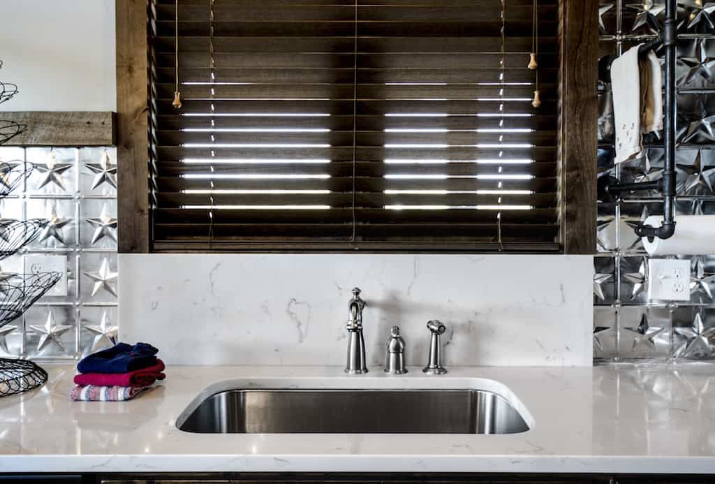 A kitchen with a sink and a window with blinds