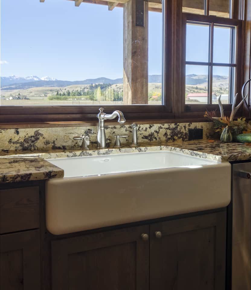 A kitchen with a sink and a window with mountains in the background