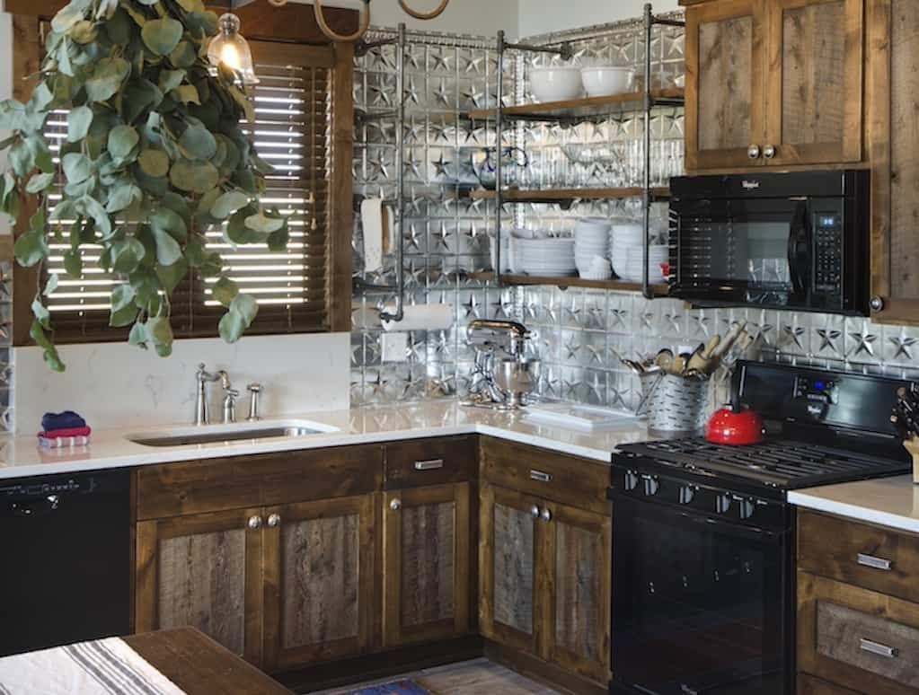 A kitchen with wooden cabinets , a stove , a sink , and a microwave.
