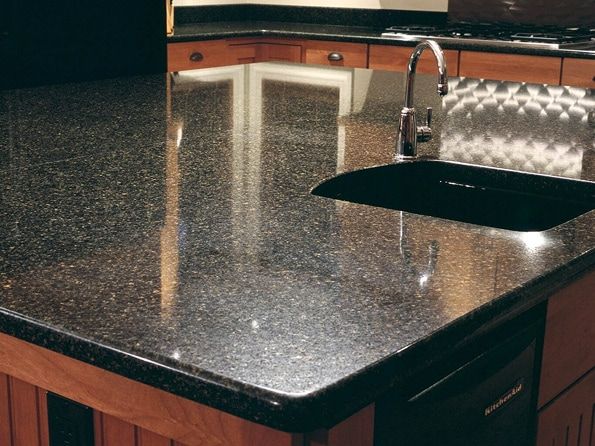 A kitchen with a black granite counter top and a black sink