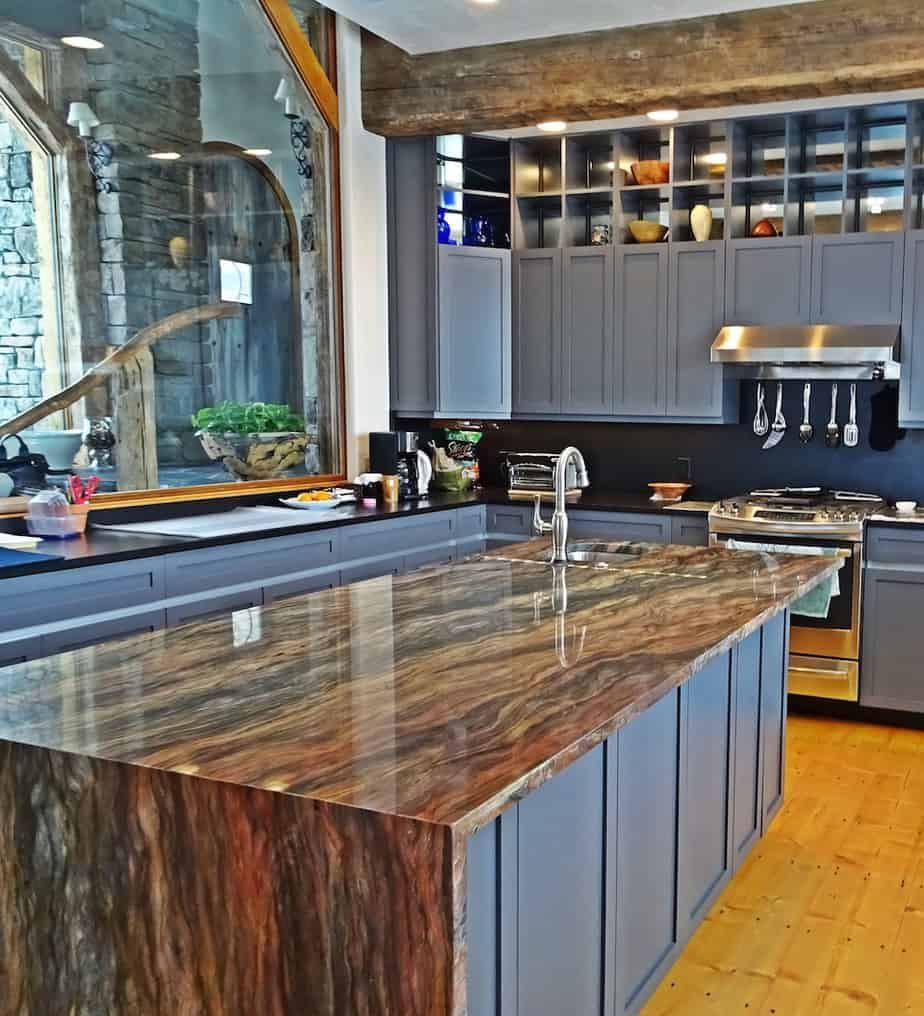 A kitchen with gray cabinets and a large granite counter top