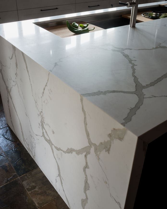 A kitchen with a marble counter top and a sink