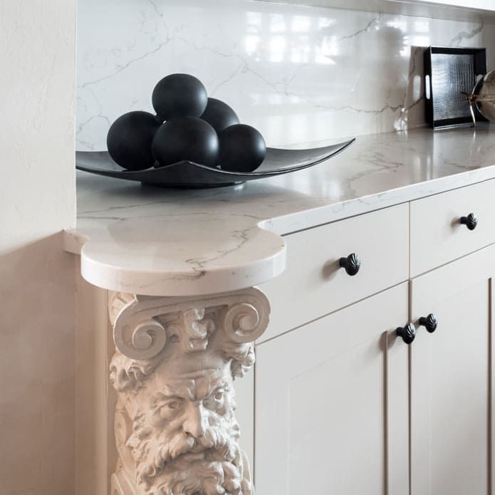 A bowl of black balls sits on a counter next to a statue of a face