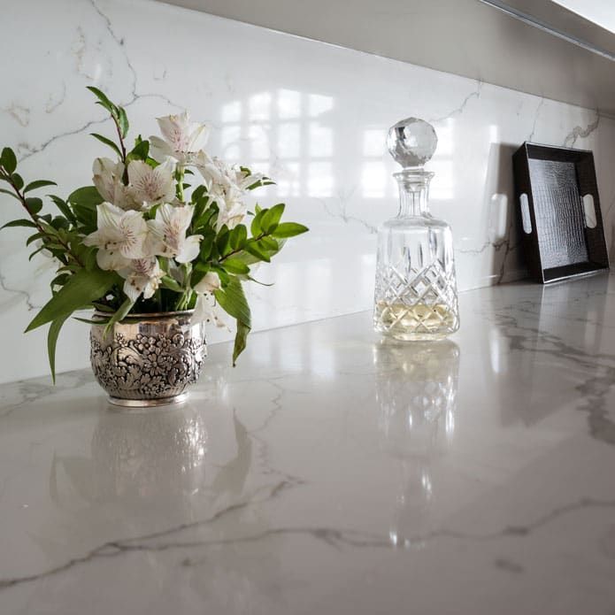 A vase of flowers is sitting on a counter next to a decanter.
