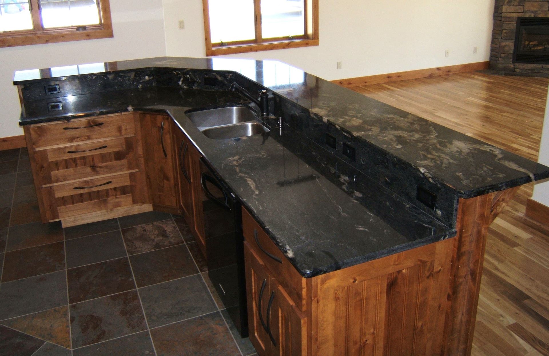 A kitchen with black granite counter tops and wooden cabinets