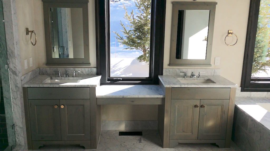 A bathroom with two sinks , two mirrors and a window.