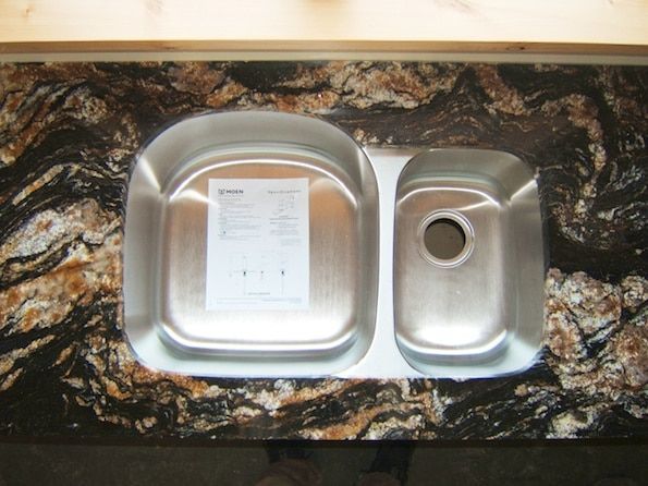 A stainless steel sink sits on a granite counter top