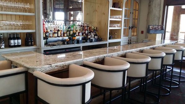 A long bar with a lot of chairs and bottles of alcohol.