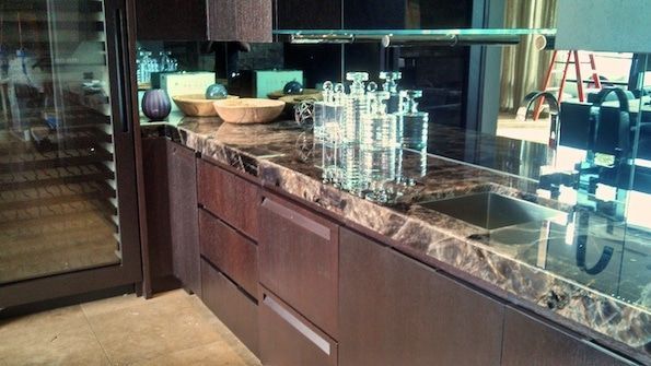 A kitchen with a marble counter top and a stainless steel sink.