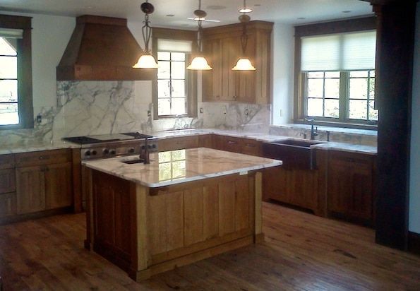 A kitchen with wooden cabinets and marble counter tops