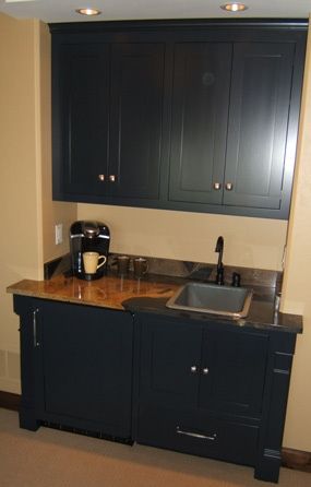 A kitchen with black cabinets and a sink