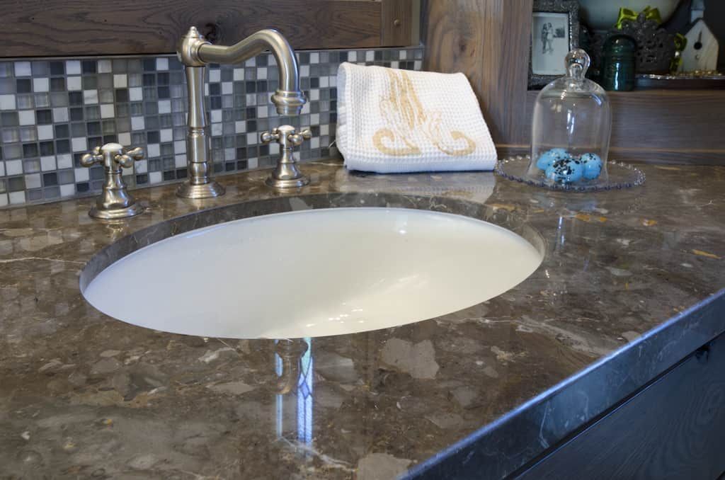 A bathroom sink with a marble counter top and a faucet.