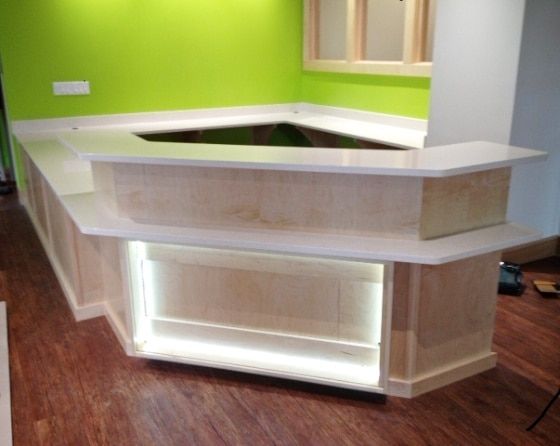 A long wooden counter in a room with a green wall