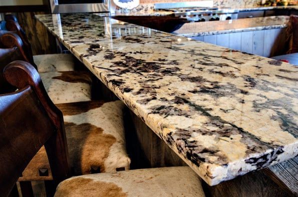 A bar with a marble counter top and cowhide stools.
