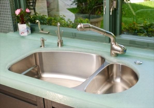 A stainless steel kitchen sink with a window in the background