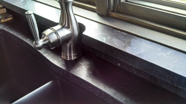 A kitchen sink with a faucet and a window in the background