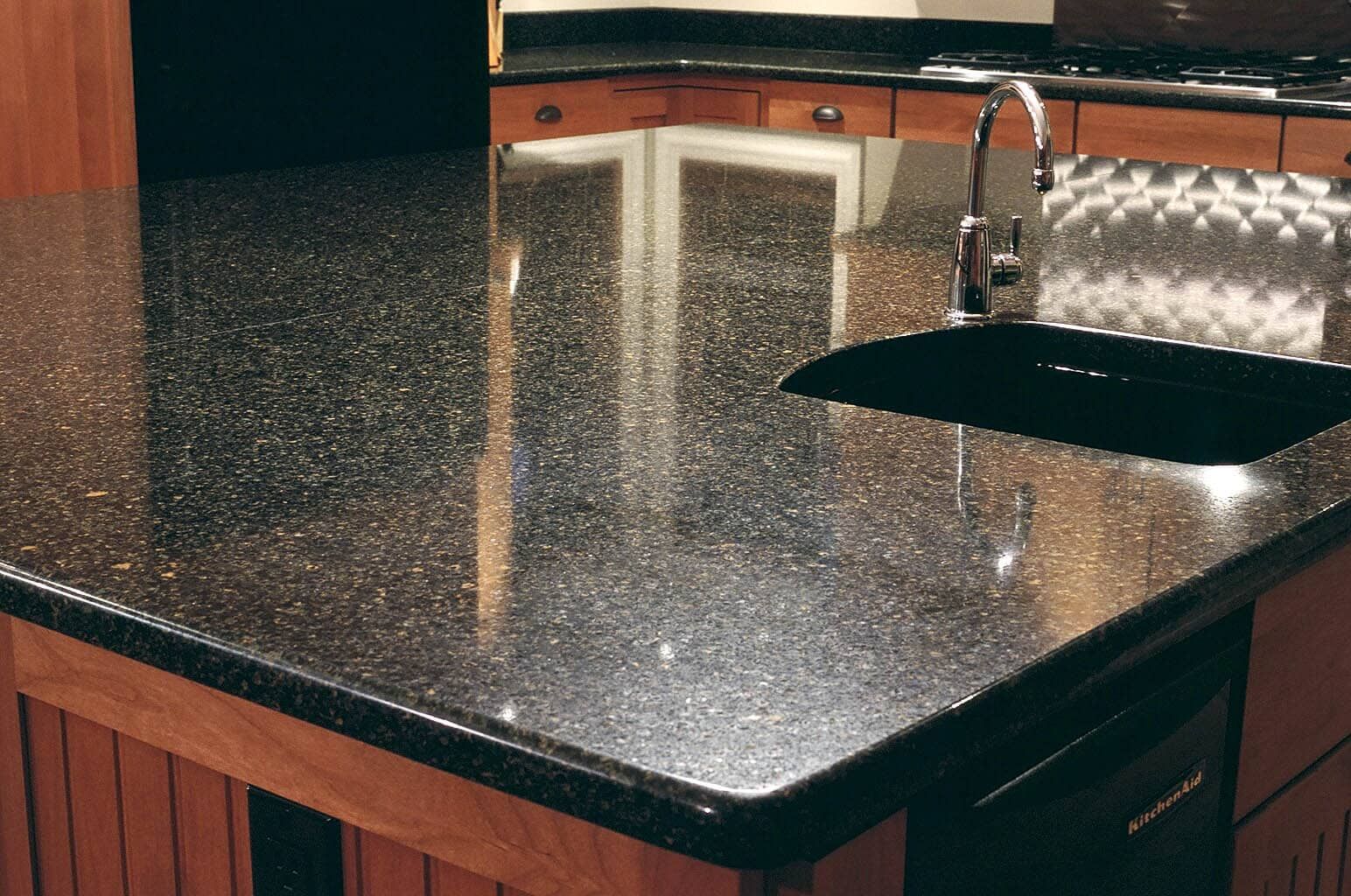A kitchen with a black granite counter top and a black sink