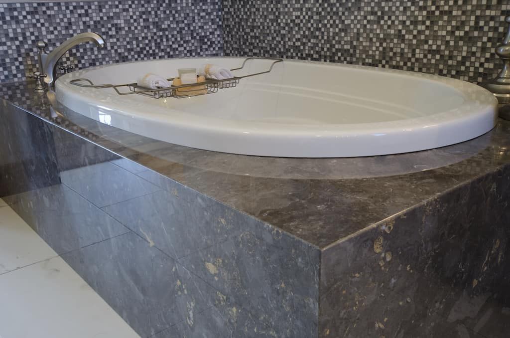 A bathtub is sitting on top of a marble counter in a bathroom.