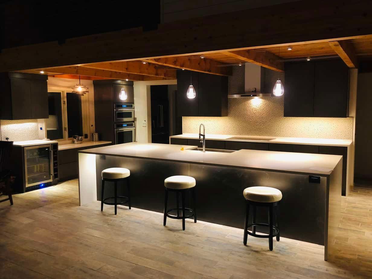 A kitchen with a large island and stools at night.