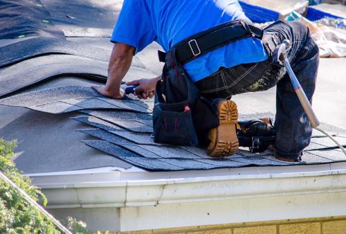 A man fixing a shingle roof