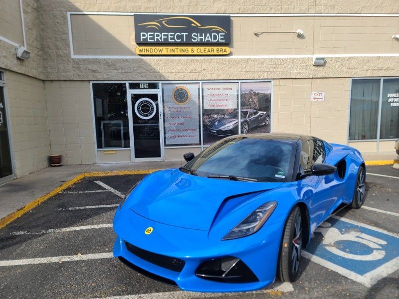 A blue sports car is parked in front of a perfect shade store.