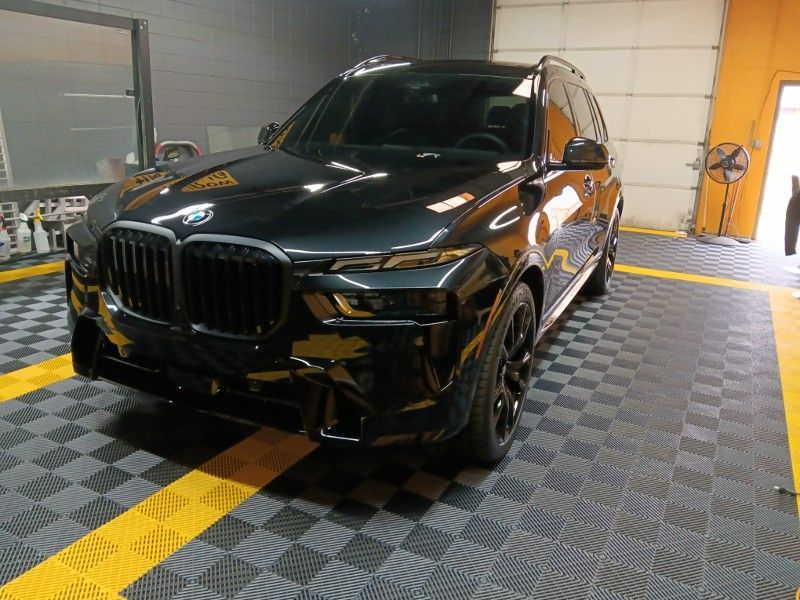 A black bmw x7 is parked in a garage.