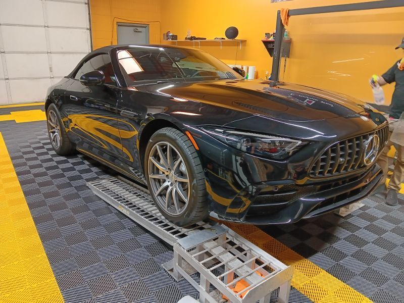 A black sports car is parked on a ramp in a garage.