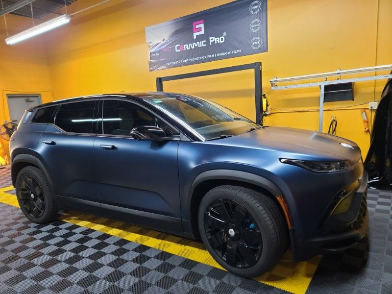 A blue car is parked in a garage with a checkered floor.