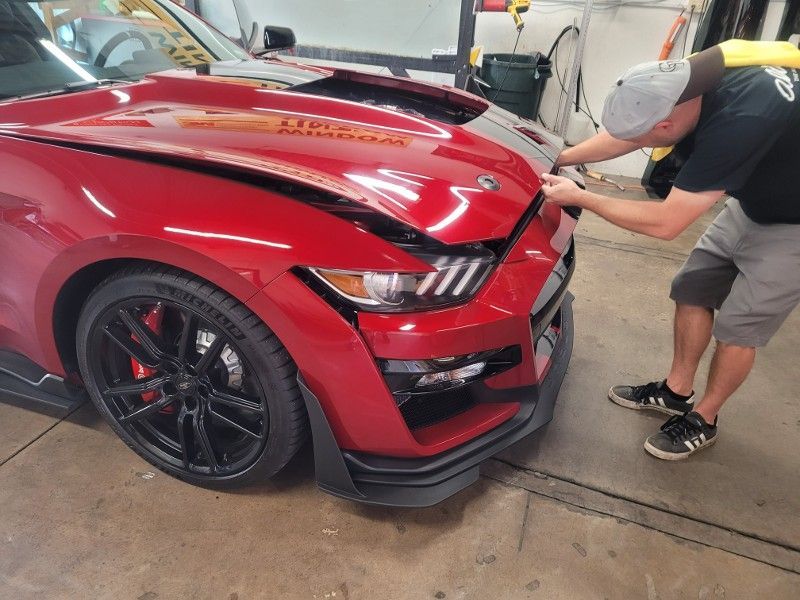 A man is working on a red mustang in a garage