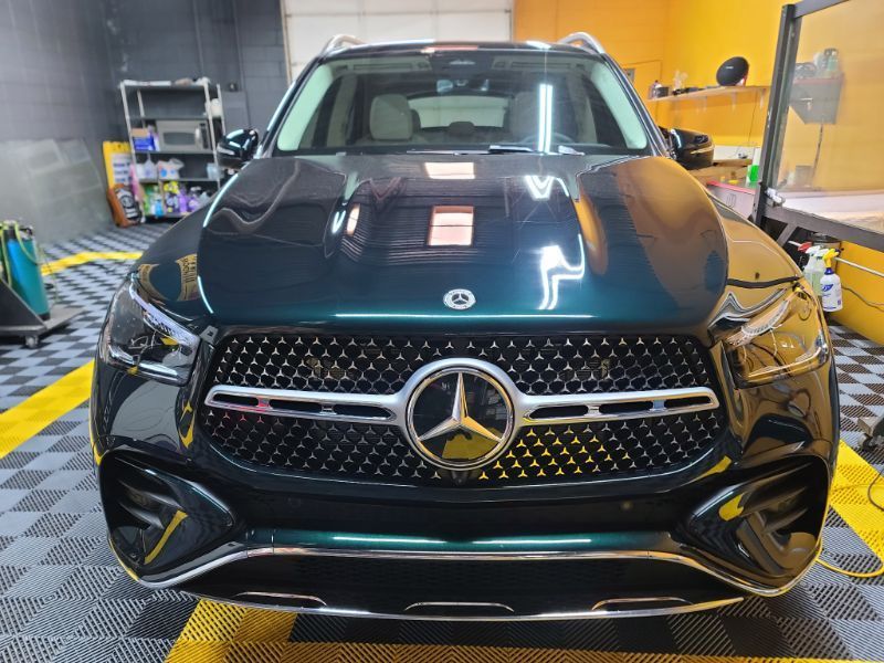 A black mercedes benz is parked in a garage.