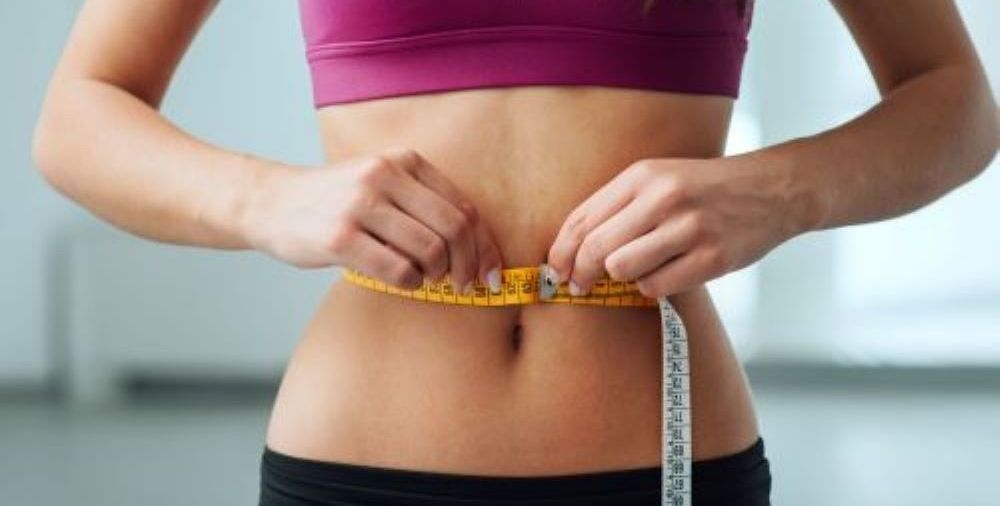 woman holding large jeans for weight loss 