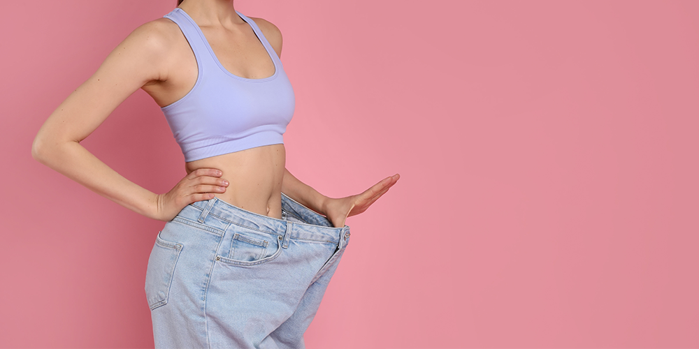 woman holding large jeans for weight loss 