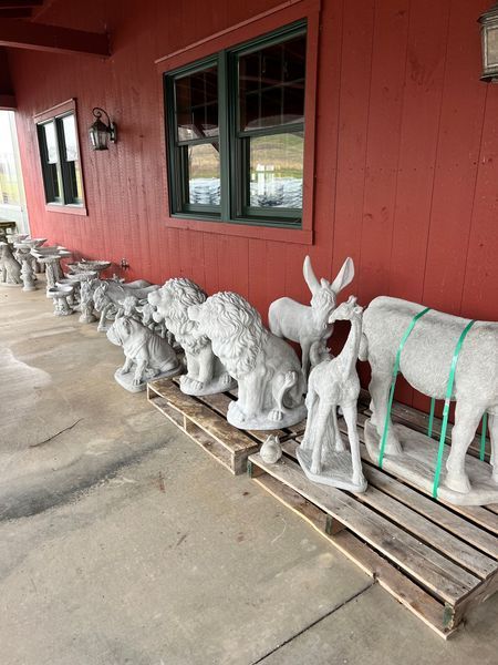 Stone animal statues on a pallet in front of a red building with a window.