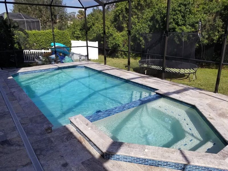 A large swimming pool with a hot tub underneath it
