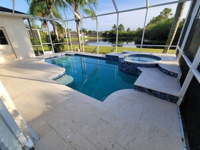 A large swimming pool with a hot tub in the backyard