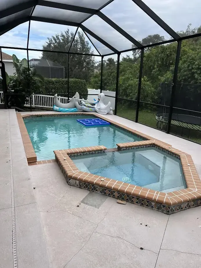 A large swimming pool with a hot tub underneath it