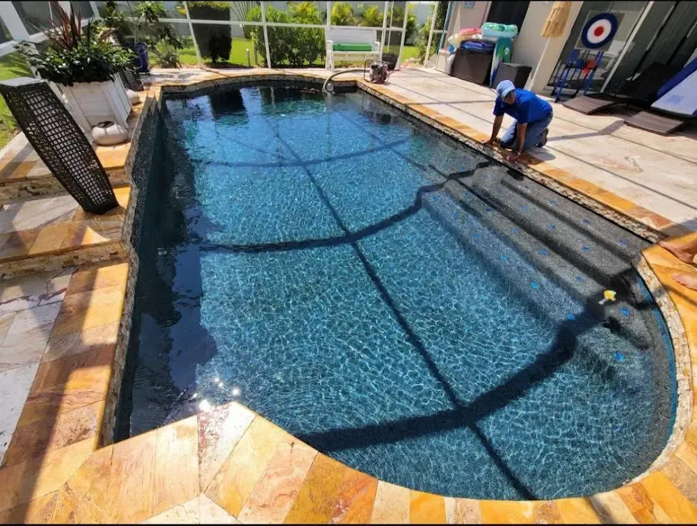 A man is cleaning a swimming pool with a vacuum cleaner