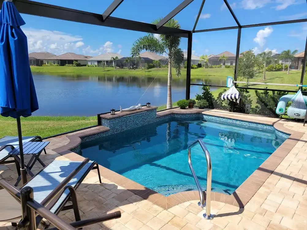 A large swimming pool is surrounded by chairs and umbrellas