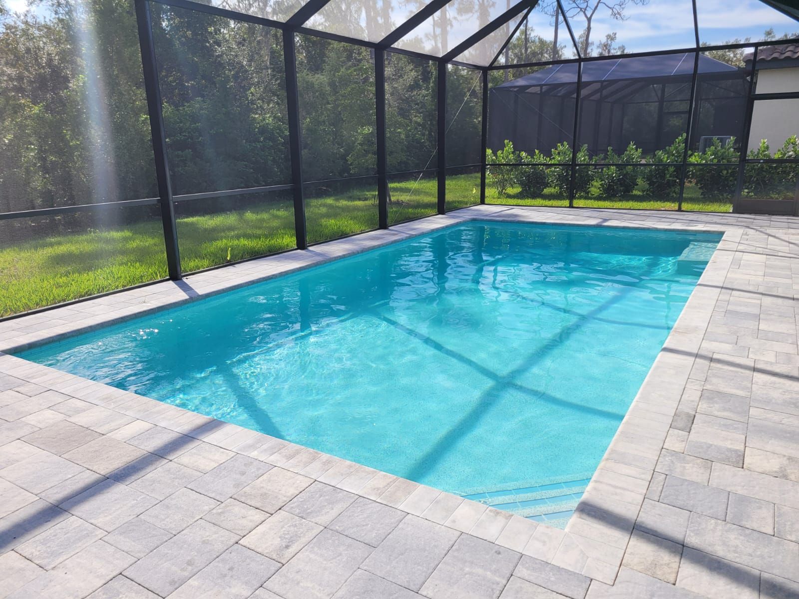 A large swimming pool is surrounded by a screened in area