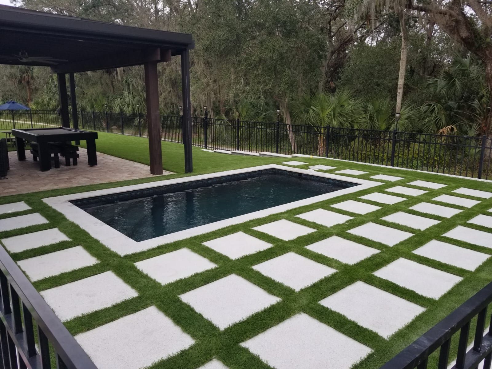 A large swimming pool is surrounded by a lush green lawn