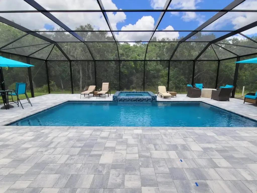 A large swimming pool surrounded by chairs and umbrellas in a screened in area