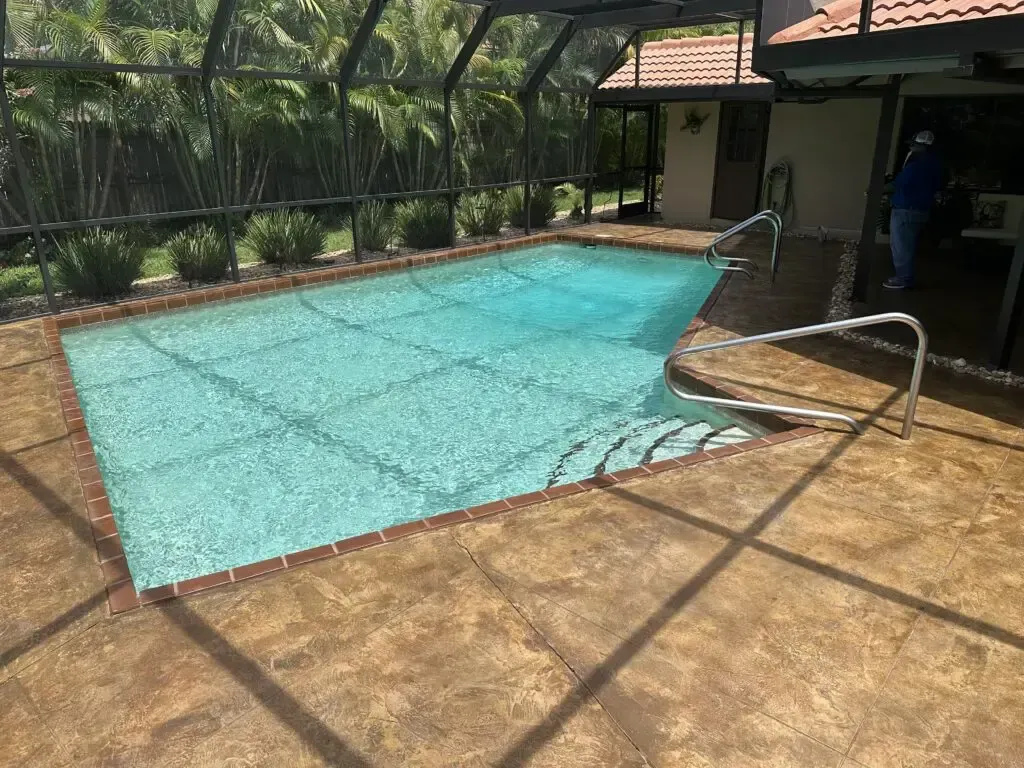 A large swimming pool is surrounded by a screened in area
