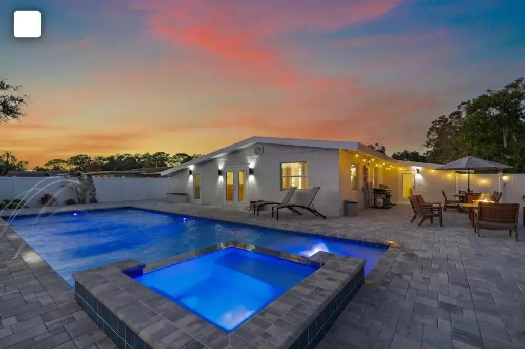 A large swimming pool with a hot tub in the backyard of a house