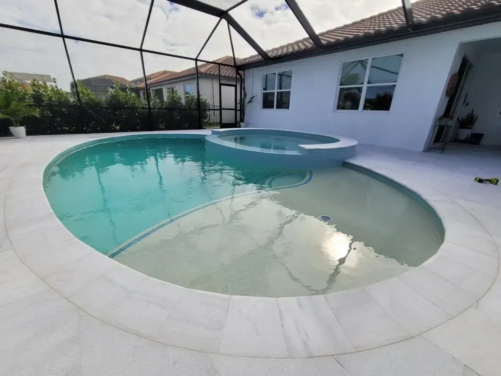 A large oval swimming pool in the backyard of a house