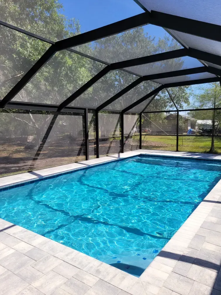 A large swimming pool is covered by a screened in area.