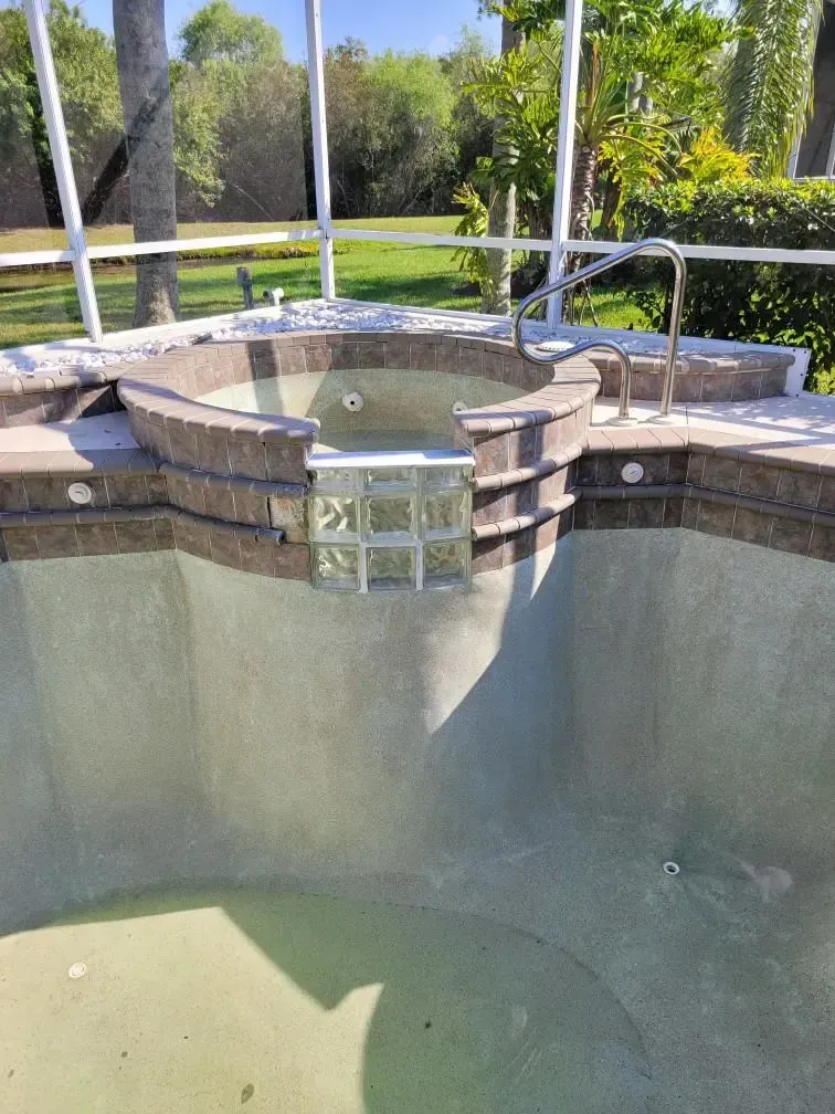 An empty swimming pool with a jacuzzi in the middle of it