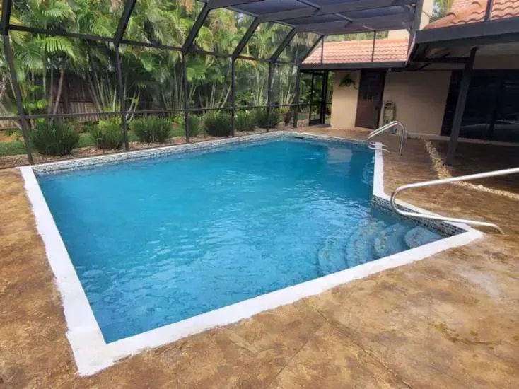 A large swimming pool is surrounded by a screened in area